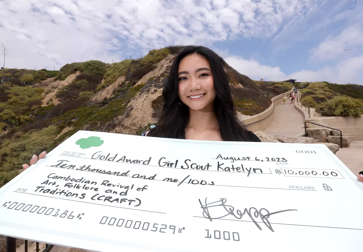 Girl Scout Katelyn Saiki stands with a large representation of her scholarship check from the Girl Scouts of the USA