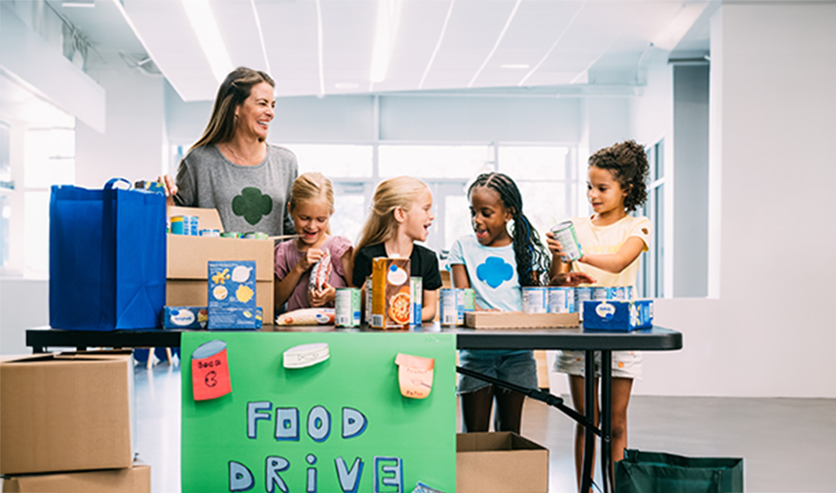 group of daisy girl scouts holding hands in uniform blue apron vest with patches and badges