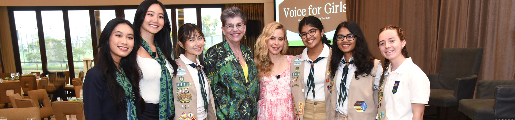  cadette girl scout hosting a table and smiling at a civics event with other middle school and high school girls  