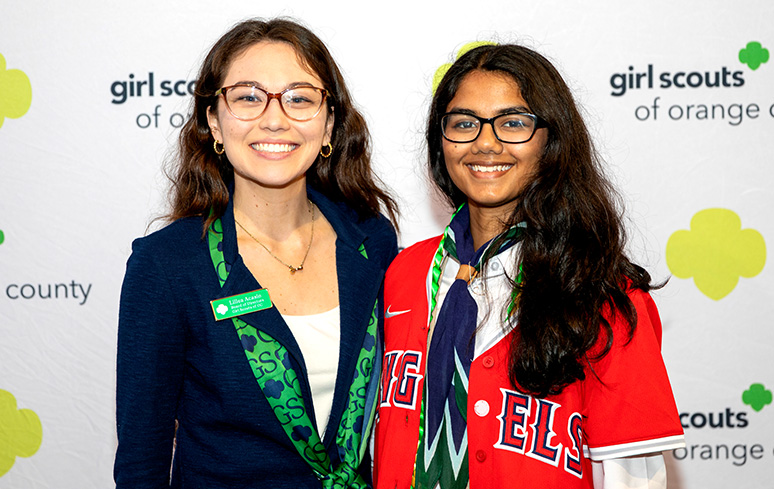 ambassador high school girl scout wearing sash outside against green background