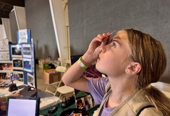 Light and Discovery: A Girl Scout Cadette explores the spectrums of light at the Optical Society of Southern California (OSSC) booth.